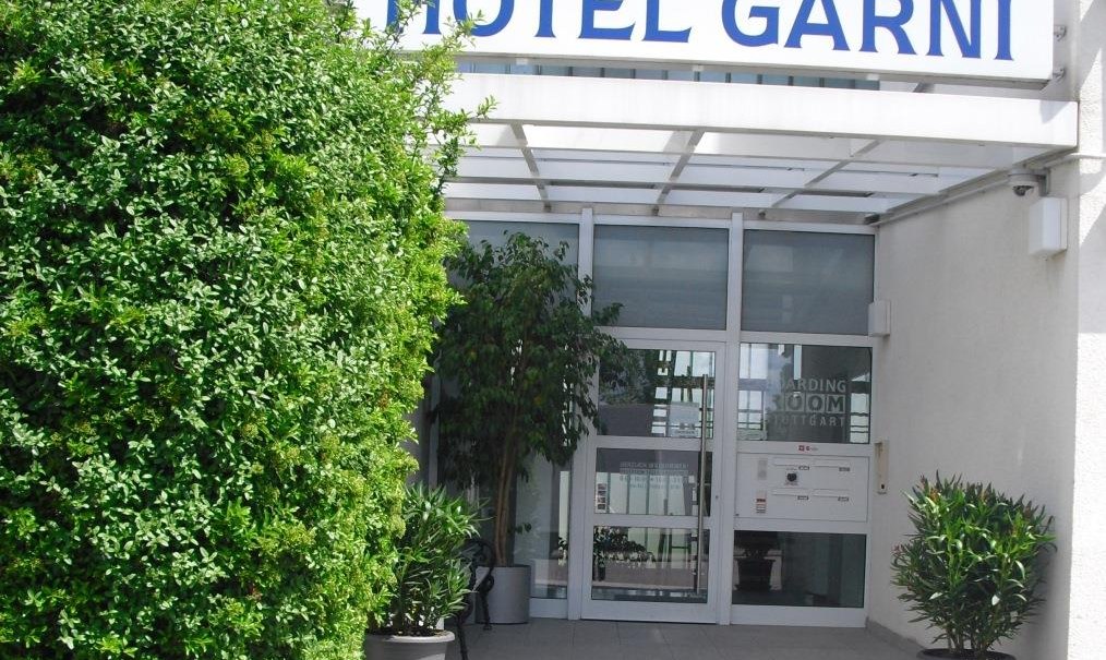 Eingang eines Hotels mit dem Schild 'Hotel Garni'. Der Bereich ist von Pflanzen umgeben und wirkt einladend., © TOMAS Eingang eines Hotels mit dem Schild 'Hotel Garni'. Der Bereich ist von Pflanzen umgeben und wirkt einladend., © TOMAS