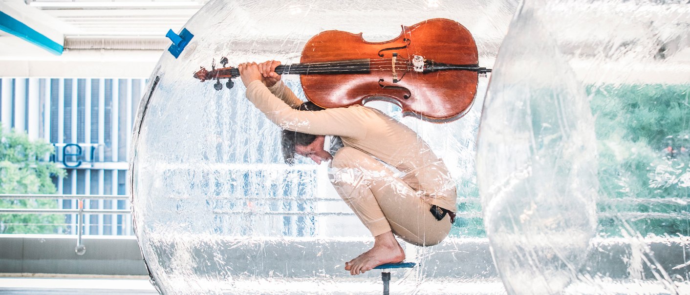Eine Person sitzt in einer durchsichtigen Kugel und hält ein Cello. Die Szene wirkt künstlerisch und ungewöhnlich., © FREDERIK LAUX PHOTOGRAPHY Eine Person sitzt in einer durchsichtigen Kugel und hält ein Cello. Die Szene wirkt künstlerisch und ungewöhnlich., © FREDERIK LAUX PHOTOGRAPHY