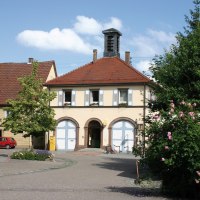 Das Rathaus in Ensingen mit rotem Ziegeldach und blauen Fensterläden, umgeben von blühenden Rosen und einem kleinen Platz., © Land der 1000 Hügel - Kraichgau-Stromberg