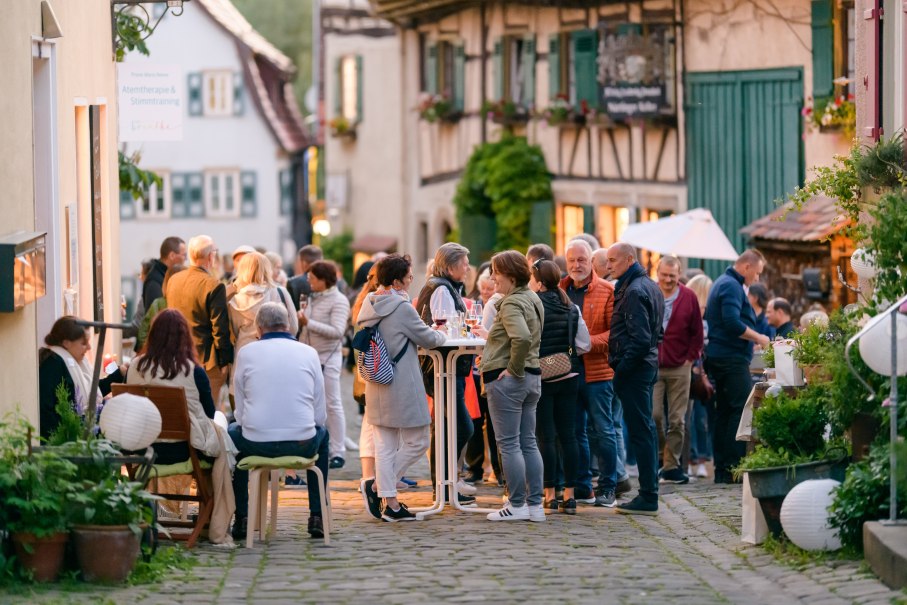 Menschen versammeln sich in einer malerischen Altstadtgasse, um bei einem Event zu essen und zu trinken. Die Atmosphäre ist lebhaft und gesellig., © Citymarketing