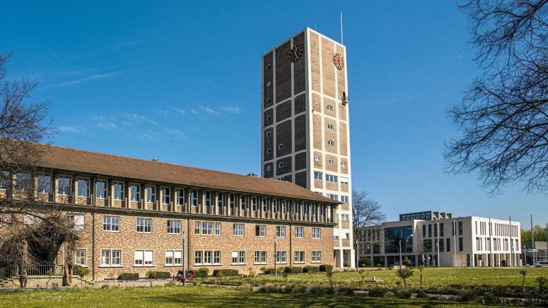 Das Rathaus Kornwestheim mit Turm und modernem Anbau, umgeben von B&auml;umen und einer Wiese unter blauem Himmel., &copy; SMG, Sarah Schmid