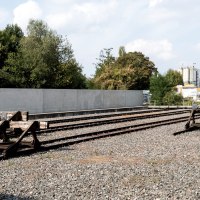 Gedenkst&auml;tte mit stillgelegten Bahngleisen, umgeben von B&auml;umen und einer Mauer. Ein ruhiger Ort des Erinnerns., &copy; Foto-Kunst Andreas Keller