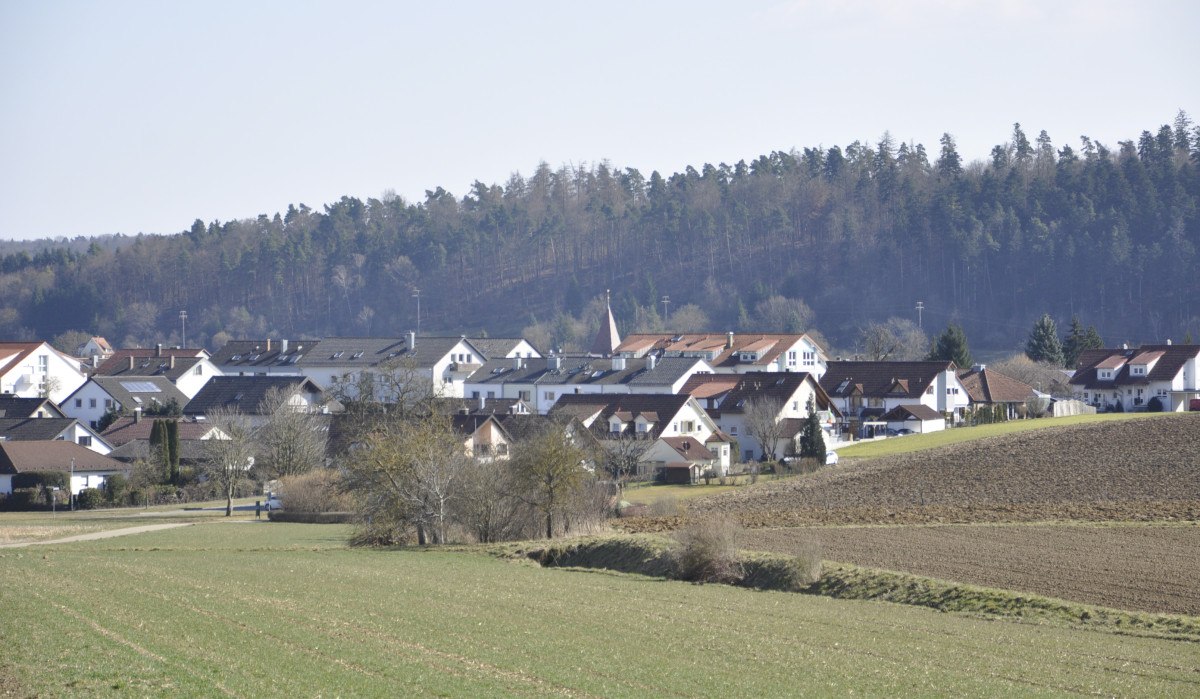 Ländliche Szene mit Häusern in Nufringen, umgeben von Feldern und einem Wald im Hintergrund unter klarem Himmel., © Natur.Nah. Schönbuch & Heckengäu Ländliche Szene mit Häusern in Nufringen, umgeben von Feldern und einem Wald im Hintergrund unter klarem Himmel., © Natur.Nah. Schönbuch & Heckengäu