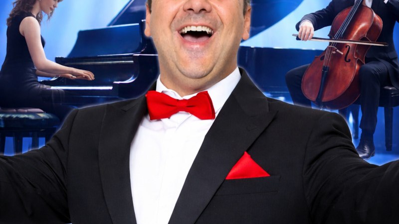 Ein Mann im Smoking steht vor einem Fl&uuml;gel auf einer B&uuml;hne. Der Schriftzug 'Andrea Bocelli Tribute' ist prominent zu sehen., &copy; Andrea Bocelli Tribute