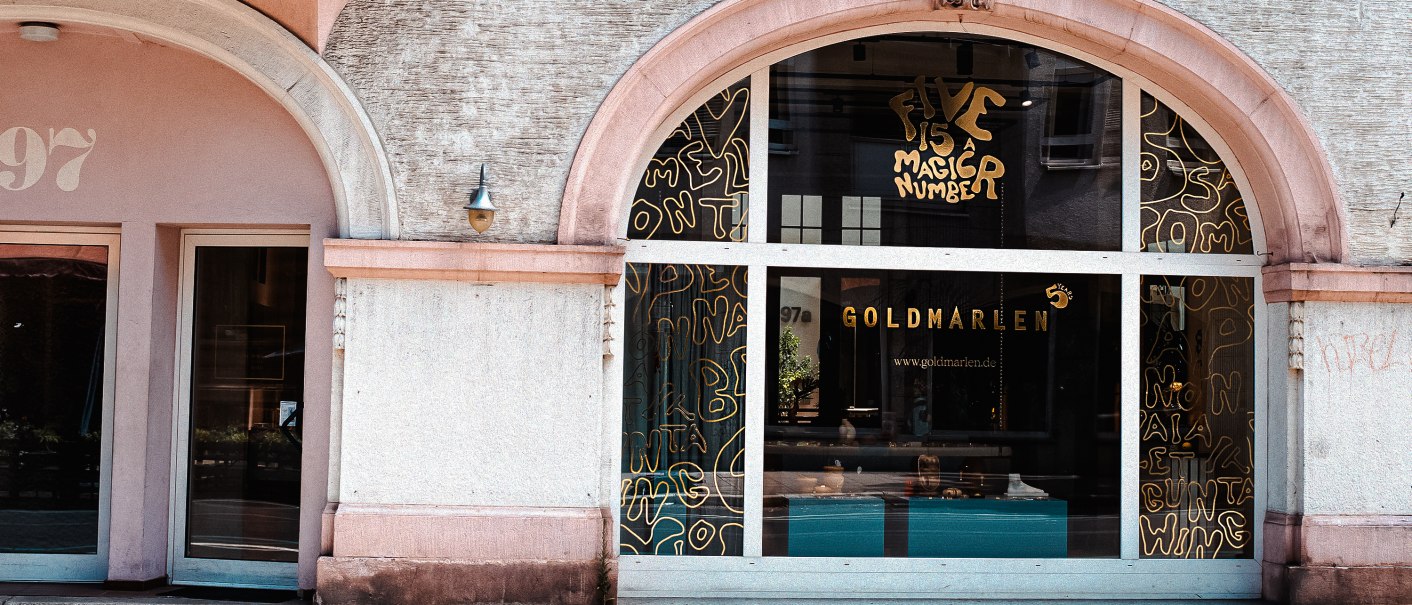 Gebäudefassade mit großen Fenstern, Aufschrift 'Goldmarlen' und dekorativen Elementen. Die Hausnummer 97 ist sichtbar., © Goldmarlen