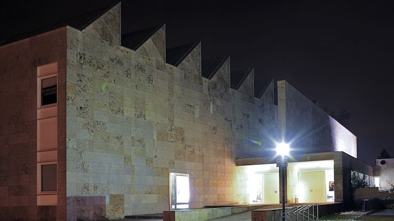 Modernes Gebäude bei Nacht mit beleuchtetem Eingang und markanter Architektur. Die Fassade ist aus Stein und das Licht erzeugt interessante Schatten., © Stadt Kornwestheim Kulturmanagement Modernes Gebäude bei Nacht mit beleuchtetem Eingang und markanter Architektur. Die Fassade ist aus Stein und das Licht erzeugt interessante Schatten., © Stadt Kornwestheim Kulturmanagement