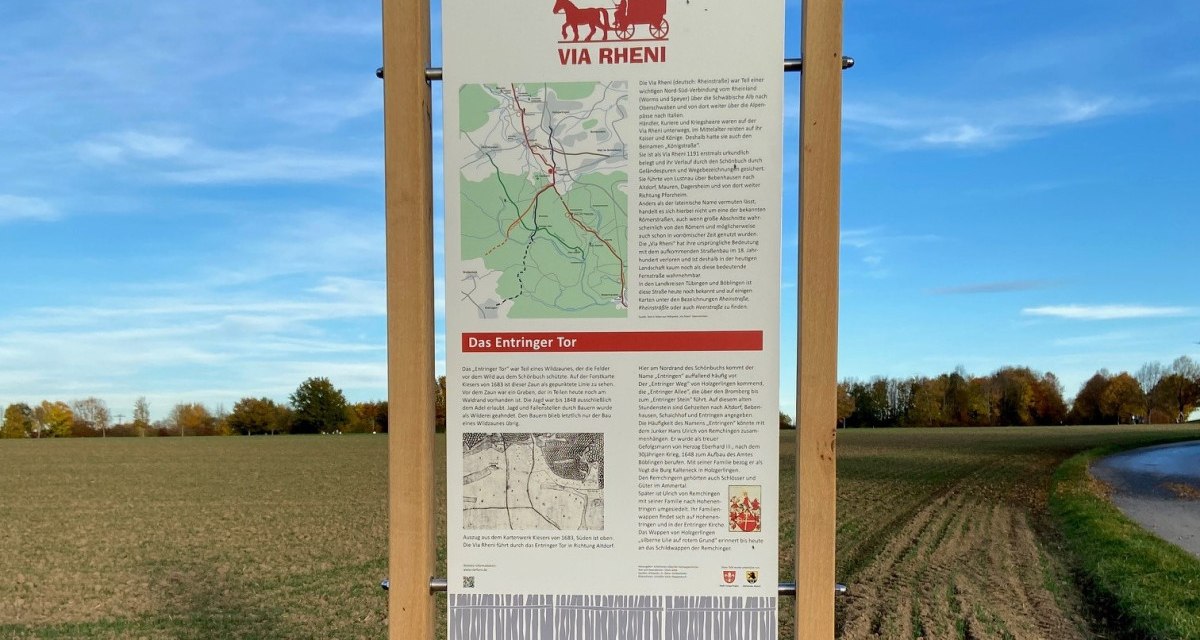 Infotafel über das Entringer Tor auf einem Feldweg, umgeben von Feldern und Bäumen, unter blauem Himmel., © Natur.Nah. Schönbuch & Heckengäu Infotafel über das Entringer Tor auf einem Feldweg, umgeben von Feldern und Bäumen, unter blauem Himmel., © Natur.Nah. Schönbuch & Heckengäu