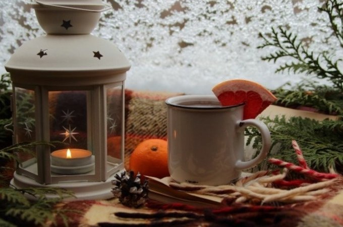 Winterliche Szene mit einer weißen Laterne, einer Tasse Glühwein mit Orangenscheibe, einer Orange und Tannenzweigen auf einer Decke., © Cool-Tours StattReisen Winterliche Szene mit einer weißen Laterne, einer Tasse Glühwein mit Orangenscheibe, einer Orange und Tannenzweigen auf einer Decke., © Cool-Tours StattReisen