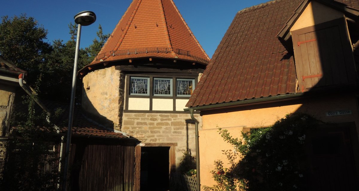 Historisches Gebäude mit rundem Turm und Fachwerkfenstern, umgeben von Häusern mit roten Dächern und blühenden Pflanzen., © Land der 1000 Hügel - Kraichgau-Stromberg Historisches Gebäude mit rundem Turm und Fachwerkfenstern, umgeben von Häusern mit roten Dächern und blühenden Pflanzen., © Land der 1000 Hügel - Kraichgau-Stromberg