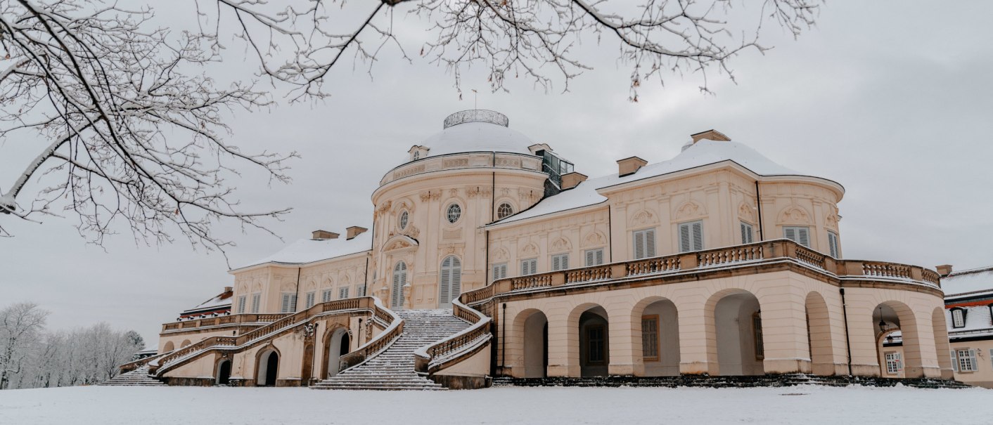 Schloss Solitude im Winter, bedeckt mit Schnee. Ein prächtiges Gebäude mit geschwungenen Treppen und kahlen Bäumen im Vordergrund., © SMG Thomas Niedermüller