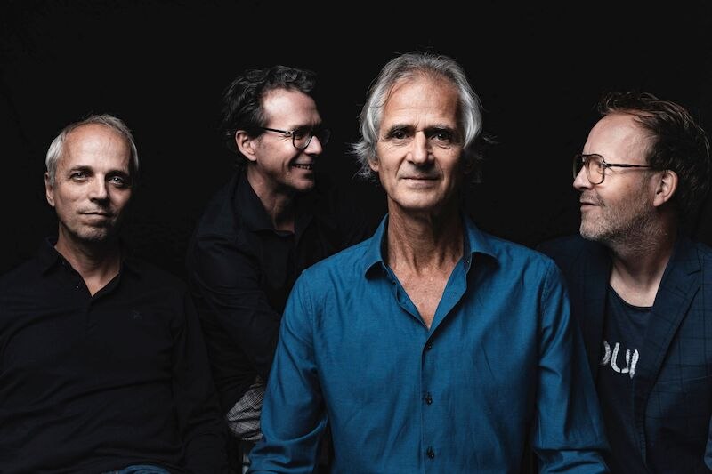 Vier M&auml;nner posieren vor einem schwarzen Hintergrund. Der Mann in der Mitte tr&auml;gt ein blaues Hemd, die anderen sind in dunkler Kleidung., &copy; Interessengemeinschaft Kultur Sindelfingen / B&ouml;blingen e.V.