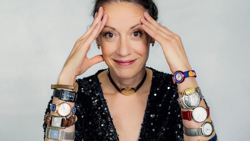 Frau mit lockigem Haar und grünem Oberteil hält eine Discokugel vor einem roten Hintergrund., © Mauerwerk GmbH