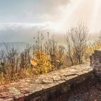 Ruinen der Burgruine Hohenstaufen, umgeben von herbstlichen Bäumen. Nebel und Sonnenstrahlen im Hintergrund schaffen eine mystische Atmosphäre., © Stuttgart-Marketing GmbH, Martina Denker
