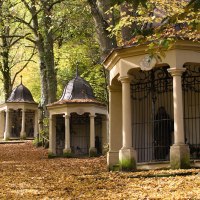 Ein herbstlicher Weg, bedeckt mit Laub, führt an kleinen Kapellen vorbei, umgeben von Bäumen., © Touristik und Marketing GmbH Schwäbisch Gmünd