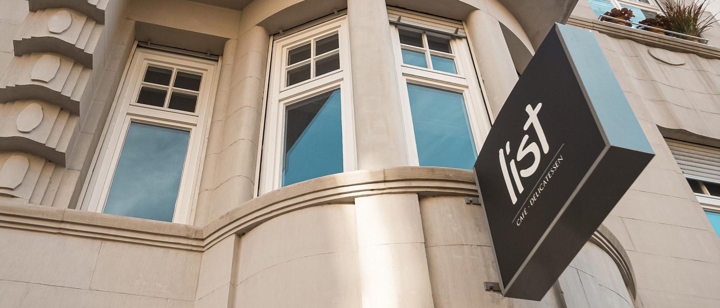 Fassade eines Gebäudes mit großen Fenstern und einem Schild mit der Aufschrift 'list Café Delicatessen'., © Café LIST, Stuttgart