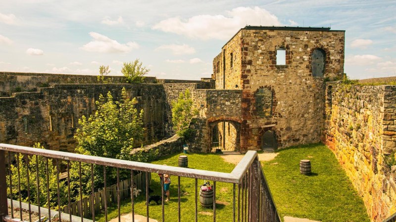 Die Ruinen der Burg Hohenrechberg in Schw&auml;bisch Gm&uuml;nd zeigen alte Steinmauern und einen gr&uuml;nen Innenhof mit B&auml;umen und F&auml;ssern., &copy; Stuttgart-Marketing GmbH, Sarah Schmid