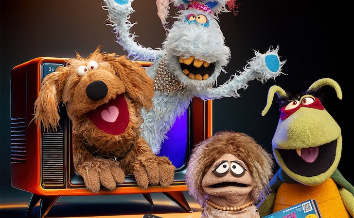 Bunte Puppen posieren fr&ouml;hlich vor einem Retro-Fernseher. Eine Puppe h&auml;lt eine Fernbedienung, eine andere ein Magazin., &copy; Scala Kultur Live gGmbH