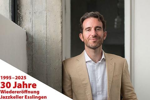 Ein Mann in beigem Anzug lächelt vor einem Türrahmen. Text: 30 Jahre Wiedereröffnung Jazzkeller Esslingen 1995–2025., © © Alejandra Barragan Ein Mann in beigem Anzug lächelt vor einem Türrahmen. Text: 30 Jahre Wiedereröffnung Jazzkeller Esslingen 1995–2025., © © Alejandra Barragan