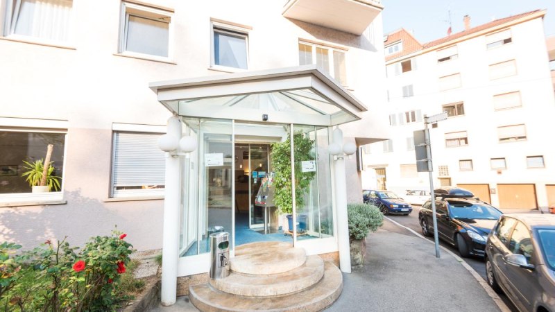 Hoteleingang mit Glasüberdachung und runden Stufen, umgeben von Autos und Pflanzen. Gebäude mit mehreren Fenstern im Hintergrund., © ARNOTEL GmbH Hoteleingang mit Glasüberdachung und runden Stufen, umgeben von Autos und Pflanzen. Gebäude mit mehreren Fenstern im Hintergrund., © ARNOTEL GmbH