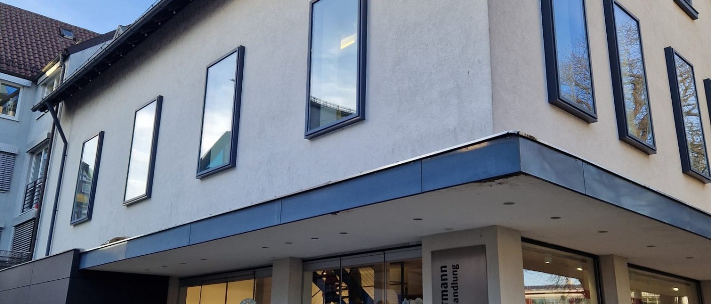 Die Buchhandlung Zimmermann zeigt eine moderne Fassade mit großen Fenstern. Vor dem Eingang stehen Tische mit Büchern zum Verkauf., © cStadtNuertingen Die Buchhandlung Zimmermann zeigt eine moderne Fassade mit großen Fenstern. Vor dem Eingang stehen Tische mit Büchern zum Verkauf., © cStadtNuertingen