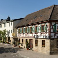 Das Hotel Adler zeigt ein traditionelles Fachwerkgebäude mit grünen Fensterläden und modernen Anbauten in einer ruhigen Straße., © Ringhotel Adler Asperg