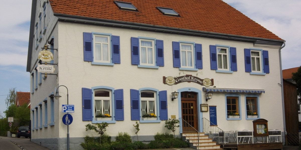 Ein traditionelles Gasthaus mit blauen Fensterläden und einem Schild mit der Aufschrift 'Gasthof Krone'., © Gasthof zur Krone