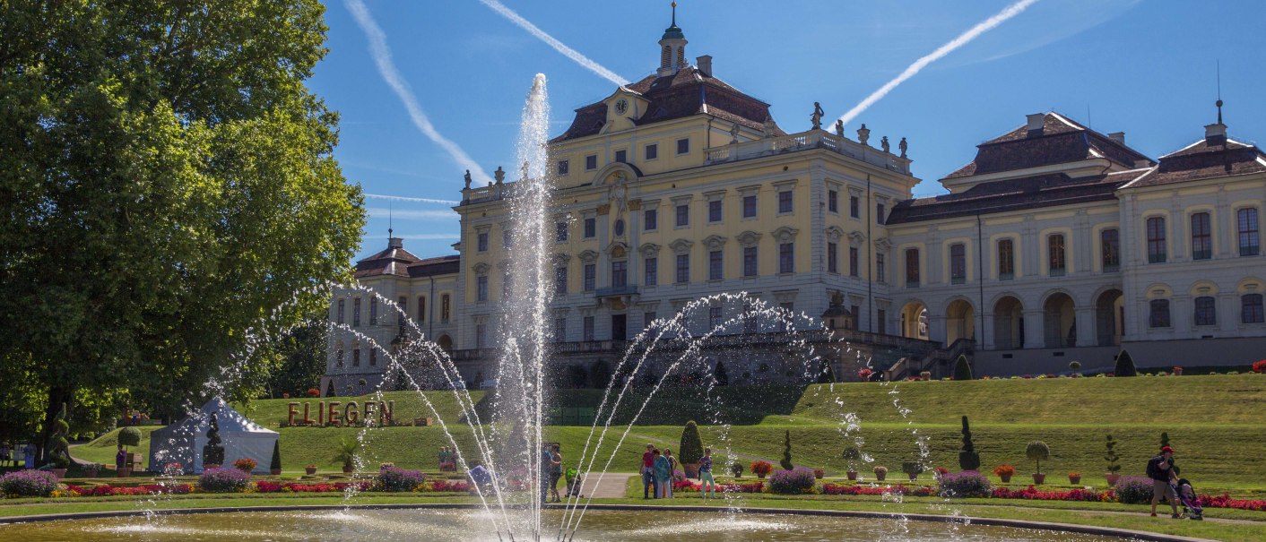 Schloss Ludwigsburg mit prächtigem Garten und Springbrunnen, umgeben von blühenden Blumen. Der Himmel ist blau mit Kondensstreifen., © Tourismus & Events Ludwigsburg Schloss Ludwigsburg mit prächtigem Garten und Springbrunnen, umgeben von blühenden Blumen. Der Himmel ist blau mit Kondensstreifen., © Tourismus & Events Ludwigsburg