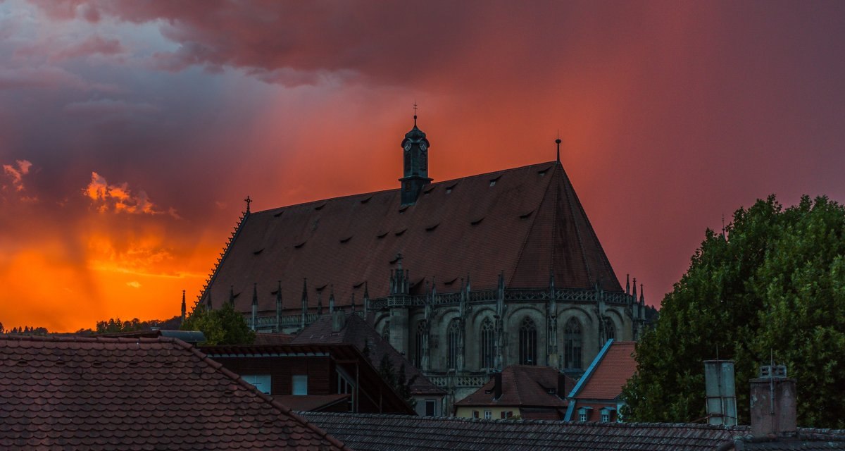 Die Kirche Heilig-Kreuz-Münster bei Sonnenuntergang. Der Himmel ist orange rot., © Foto: Mario Klaiber Die Kirche Heilig-Kreuz-Münster bei Sonnenuntergang. Der Himmel ist orange rot., © Foto: Mario Klaiber