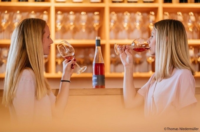 Zwei Frauen genießen eine Weinprobe im Weinbaumuseum. Sie halten Weingläser mit roséfarbenem Wein, im Hintergrund sind Gläserregale zu sehen., © Stuttgart-Marketing GmbH, Thomas Niedermüller