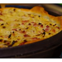 Ein frisch gebackener Zwiebelkuchen in einer runden Backform, goldbraun und mit Speckstückchen belegt., © WTM GmbH Waiblingen