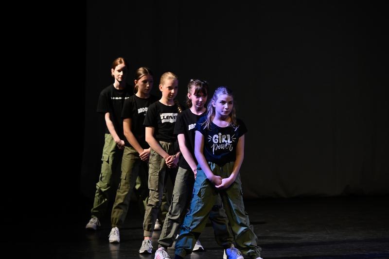 Fünf Kinder in schwarzen T-Shirts und grünen Hosen tanzen auf einer Bühne. Sie stehen in einer Reihe und tragen weiße Turnschuhe., © Kunstschule Labyrinth Fünf Kinder in schwarzen T-Shirts und grünen Hosen tanzen auf einer Bühne. Sie stehen in einer Reihe und tragen weiße Turnschuhe., © Kunstschule Labyrinth