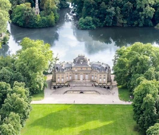 Luftaufnahme von Schloss Monrepos, umgeben von &uuml;ppigem Gr&uuml;n und einem See. Das Schloss liegt zentral in einer gepflegten Parklandschaft., &copy; TheWeekend