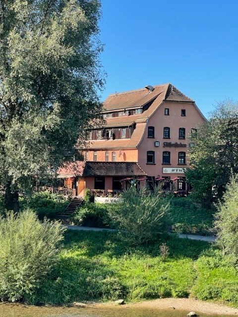 Ein mehrstöckiges Gebäude mit rotem Dach und dem Schriftzug "Stiftskeller". Es ist von Bäumen und Grünflächen umgeben, der Himmel ist klar und blau., © cAvada Ein mehrstöckiges Gebäude mit rotem Dach und dem Schriftzug "Stiftskeller". Es ist von Bäumen und Grünflächen umgeben, der Himmel ist klar und blau., © cAvada