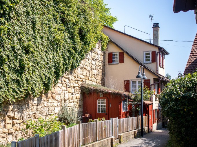 Ein idyllischer Weg in Schw&auml;bisch Gm&uuml;nd mit einem charmanten Haus, roten Fensterl&auml;den und einer efeubewachsenen Steinmauer., &copy; Touristik und Marketing GmbH