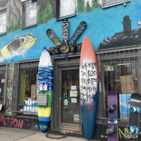 Surf- und Sportshop mit bunter Fassade, Surfbrettern und Snowboards vor dem Eingang. Graffiti und Wandmalereien schm&uuml;cken das Geb&auml;ude., &copy; L. Besmer