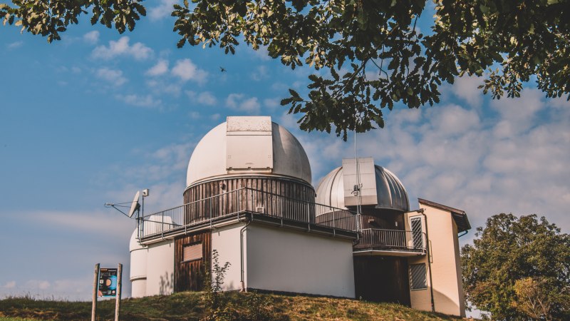 Ein Observatorium mit zwei Kuppeln steht auf einem H&uuml;gel unter blauem Himmel. B&auml;ume rahmen das Bild ein., &copy; Stadt Welzheim