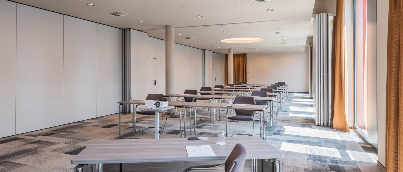 Moderner Konferenzraum mit Tischen, Stühlen, Deckenbeleuchtung und großen Fenstern im Hilton Garden Inn., © Hilton Garden Inn Stuttgart Neckarpark Moderner Konferenzraum mit Tischen, Stühlen, Deckenbeleuchtung und großen Fenstern im Hilton Garden Inn., © Hilton Garden Inn Stuttgart Neckarpark