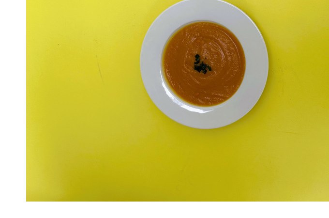 Ein weißer Teller mit orangefarbener Suppe, garniert mit Kräutern, auf einem leuchtend gelben Hintergrund., © Kunsthalle Göppingen Ein weißer Teller mit orangefarbener Suppe, garniert mit Kräutern, auf einem leuchtend gelben Hintergrund., © Kunsthalle Göppingen