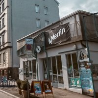 Stra&szlig;enszene in Stuttgart mit dem Kulturzentrum Merlin e.V. rechts im Bild. Die Sonne scheint, Autos parken entlang der Stra&szlig;e., &copy; Merlin, Stuttgart
