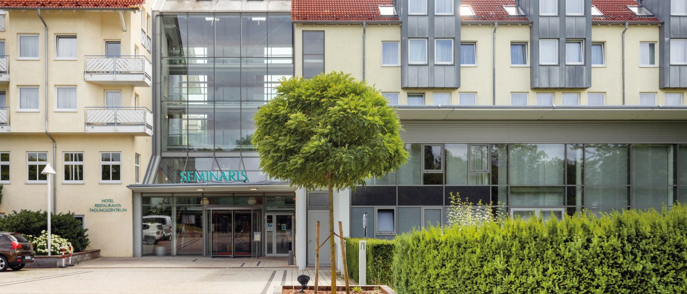 Moderner Hoteleingang mit Glasfassade, rotem Dach und gepflegter Umgebung. Der Name 'Seminaris' ist über dem Eingang sichtbar., © Seminaris Hotel Bad Boll Moderner Hoteleingang mit Glasfassade, rotem Dach und gepflegter Umgebung. Der Name 'Seminaris' ist über dem Eingang sichtbar., © Seminaris Hotel Bad Boll