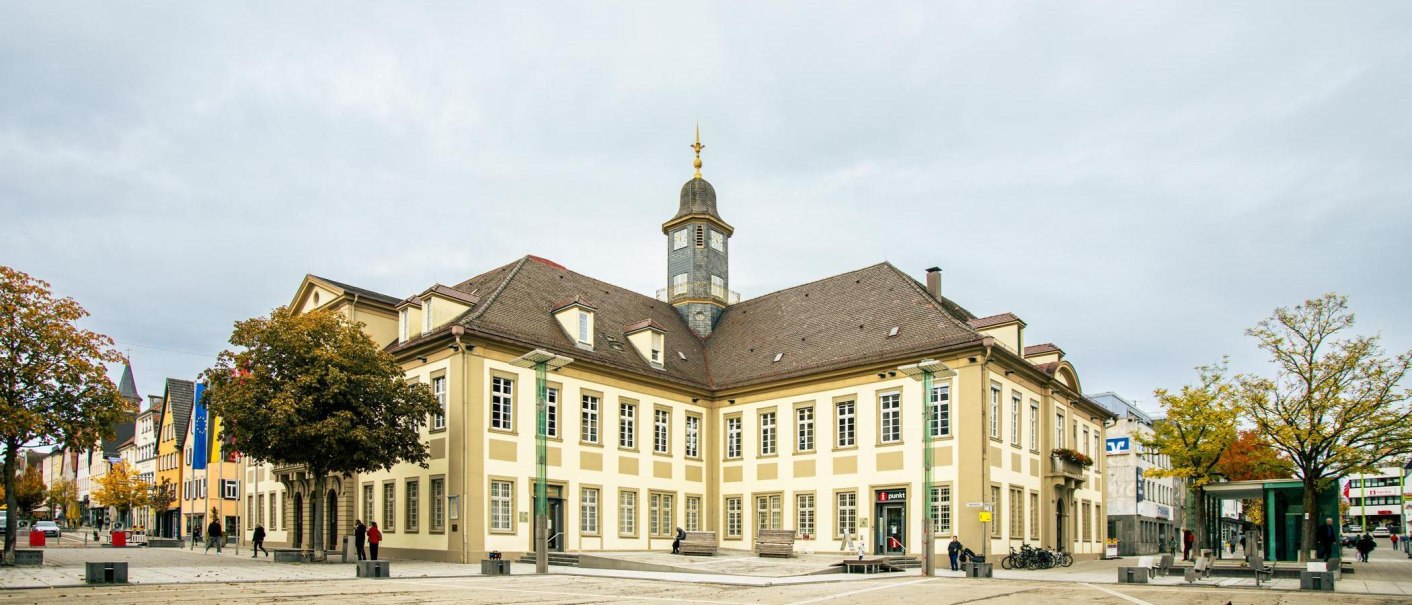 Das Rathaus von Göppingen auf dem Marktplatz, umgeben von Bäumen und Menschen. Der Uhrturm ragt in den bewölkten Himmel., © Stuttgart-Marketing GmbH, Sarah Schmid Das Rathaus von Göppingen auf dem Marktplatz, umgeben von Bäumen und Menschen. Der Uhrturm ragt in den bewölkten Himmel., © Stuttgart-Marketing GmbH, Sarah Schmid