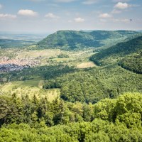 Blick von der Burg Hohenneuffen auf das Dorf Beuren, umgeben von grünen Wäldern und Hügeln unter einem blauen Himmel mit wenigen Wolken., © hochgehberge Blick von der Burg Hohenneuffen auf das Dorf Beuren, umgeben von grünen Wäldern und Hügeln unter einem blauen Himmel mit wenigen Wolken., © hochgehberge