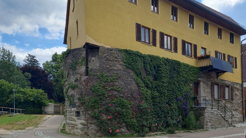 Stadtmauer und ehemaliger Wachturm in der Grabenstra&szlig;e - Gelbes Haus an der Stra&szlig;e. Die Au&szlig;enwand des Erdgeschoss ist die alte Stadtmauer. Sie besteht aus gro&szlig;en gemauerten Steinen und ist mit Efeu bewachsen. Der Himmel ist leicht bew&ouml;lkt., &copy; Petra Natzkowski