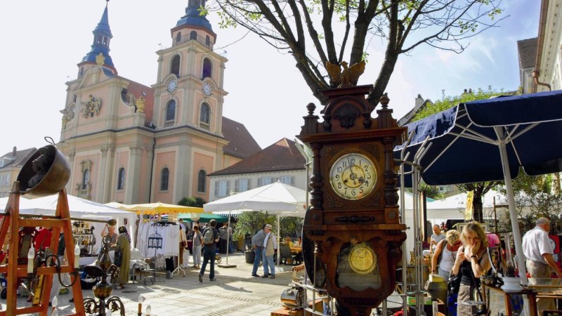 Antikmarkt in Ludwigsburg mit Ständen voller Antiquitäten. Im Hintergrund ist eine Kirche zu sehen. Besucher schlendern durch die Stände., © Tourismus & Events Ludwigsburg Antikmarkt in Ludwigsburg mit Ständen voller Antiquitäten. Im Hintergrund ist eine Kirche zu sehen. Besucher schlendern durch die Stände., © Tourismus & Events Ludwigsburg