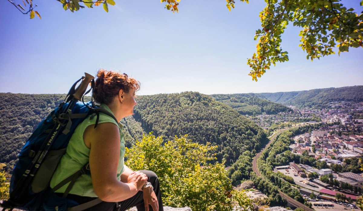 Frau mit Rucksack genießt den Ausblick vom Anwandfelsen auf Geislingen und das umliegende bewaldete Tal., © Stadt Geislingen an der Steige Frau mit Rucksack genießt den Ausblick vom Anwandfelsen auf Geislingen und das umliegende bewaldete Tal., © Stadt Geislingen an der Steige