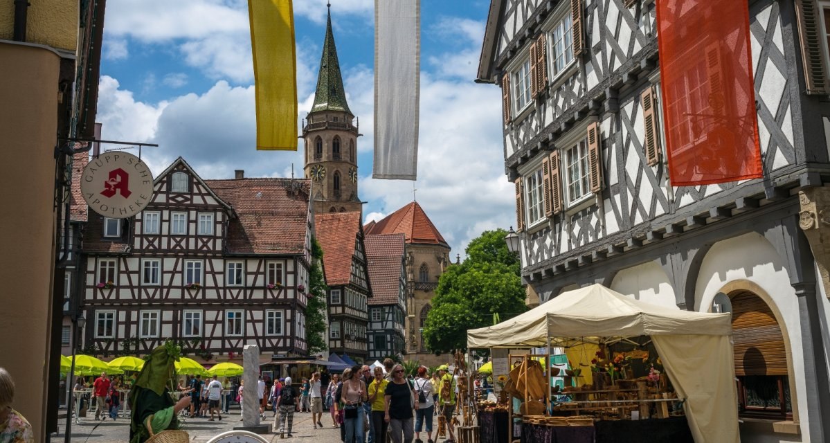 Historischer Marktplatz in Schorndorf mit Fachwerkh&auml;usern, Kirchturm im Hintergrund und Marktst&auml;nden. Menschen flanieren bei sonnigem Wetter., &copy; Remstal Tourismus e.V.