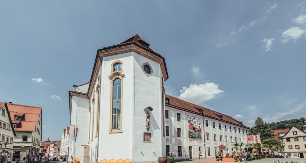 Das Museum im Prediger in Schwäbisch Gmünd, ein historisches Gebäude mit weißen Wänden und roten Dächern, bei sonnigem Wetter. Menschen und Pflanzen im Vordergrund., © Tourismus Ostalb, Fotograf: Christian Frumolt Das Museum im Prediger in Schwäbisch Gmünd, ein historisches Gebäude mit weißen Wänden und roten Dächern, bei sonnigem Wetter. Menschen und Pflanzen im Vordergrund., © Tourismus Ostalb, Fotograf: Christian Frumolt