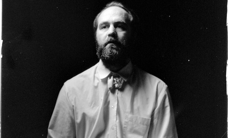 Schwarz-wei&szlig; Portr&auml;t eines b&auml;rtigen Mannes in Hemd und Fliege vor dunklem Hintergrund., &copy; Kulturhaus Schwanen