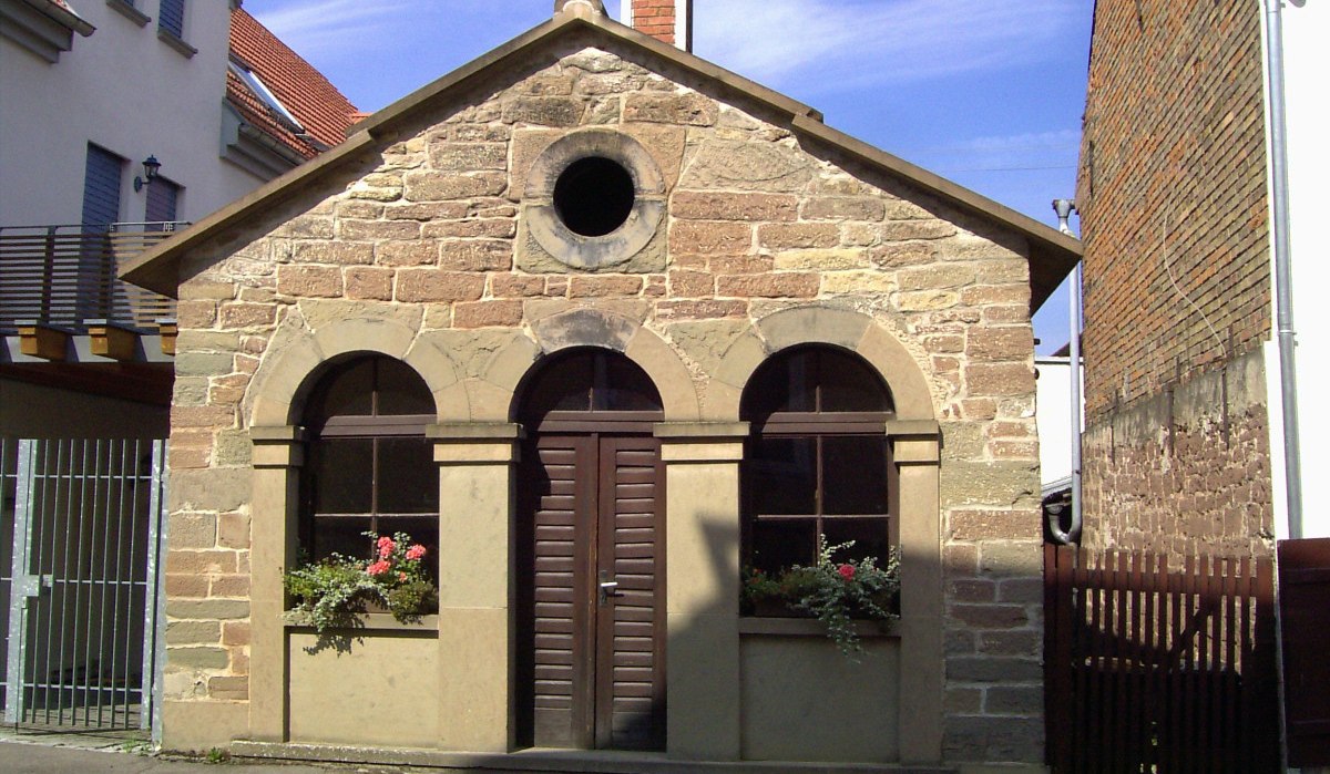 Historisches Backhaus aus Sandstein mit Rundbogenfenstern, Blumen in den Fensterkästen, umgeben von modernen Gebäuden., © Land der 1000 Hügel - Kraichgau-Stromberg Historisches Backhaus aus Sandstein mit Rundbogenfenstern, Blumen in den Fensterkästen, umgeben von modernen Gebäuden., © Land der 1000 Hügel - Kraichgau-Stromberg
