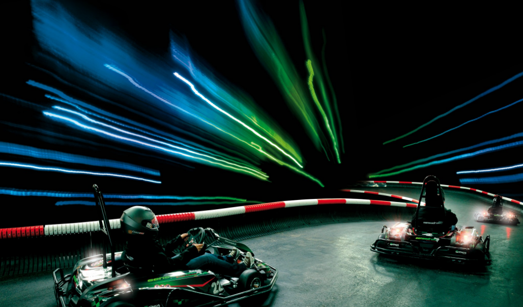 Zwei Karts fahren auf einer beleuchteten Indoor-Strecke. Lichtstreifen in Blau und Grün erzeugen einen dynamischen Effekt., © Sensapolis Sindelfingen Zwei Karts fahren auf einer beleuchteten Indoor-Strecke. Lichtstreifen in Blau und Grün erzeugen einen dynamischen Effekt., © Sensapolis Sindelfingen
